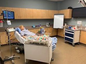 A simulation lab mannequin in a hospital bed.